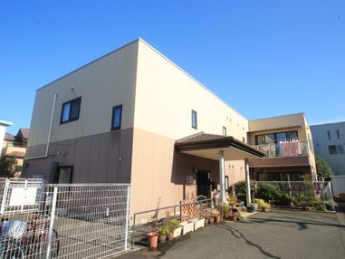 建物は2階建てで外壁の色が上部と下部で分かれている。玄関先に車をつけられるようなスペースがある。駐輪場が併設されている。