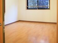 「愛の家グループホーム 練馬早宮」居室。明るいフローリングが広がっており、奥に窓が１つ設置されている。