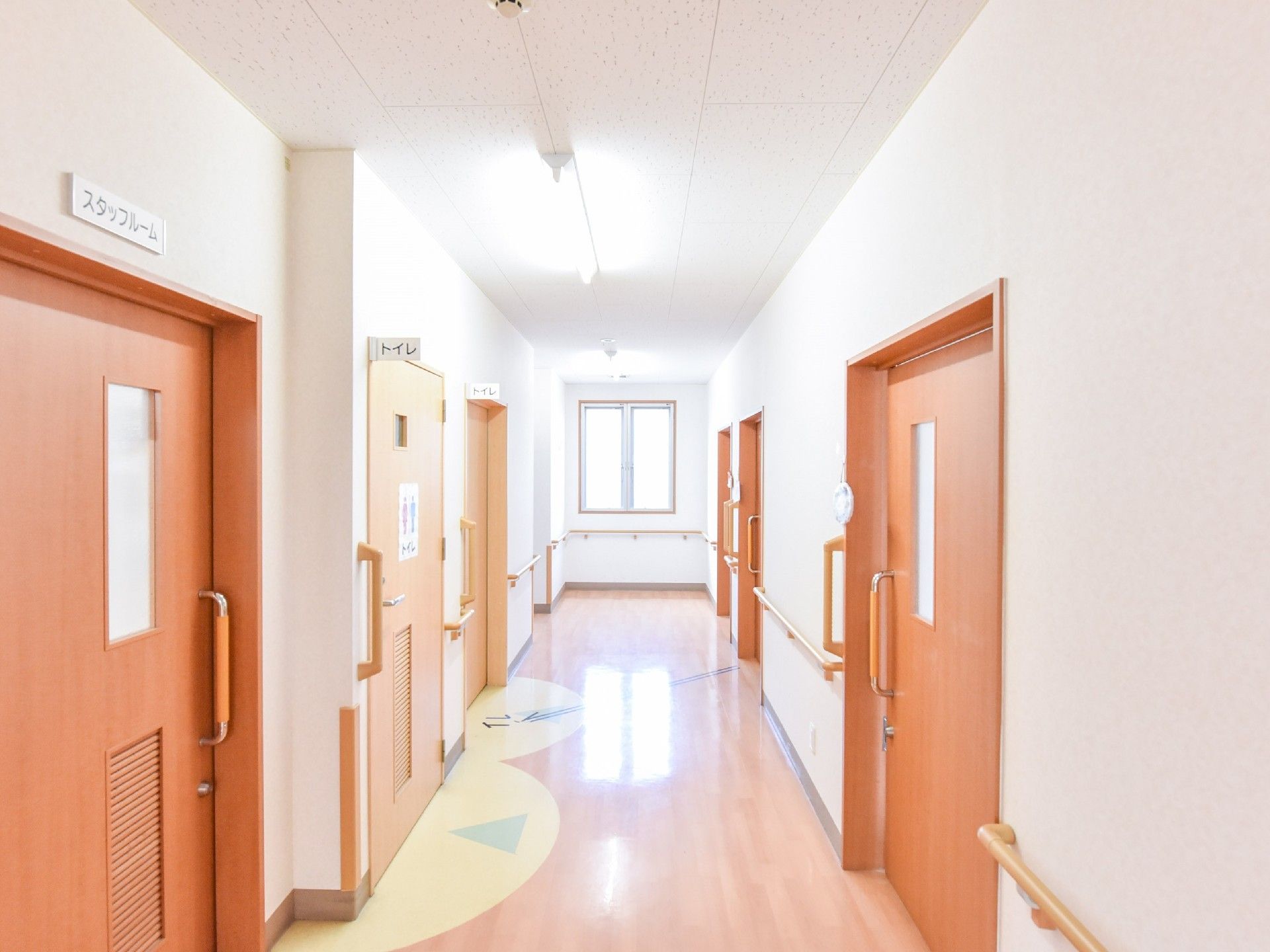 廊下はフラットなフローリングで段差がない。各部屋の入り口にはわかりやすく表札が出ている。奥に大きな窓があり明るい。