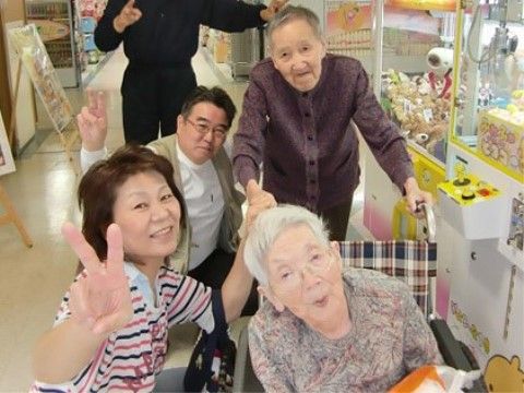 ゲームセンターで記念写真を撮るご入居者様とスタッフ。