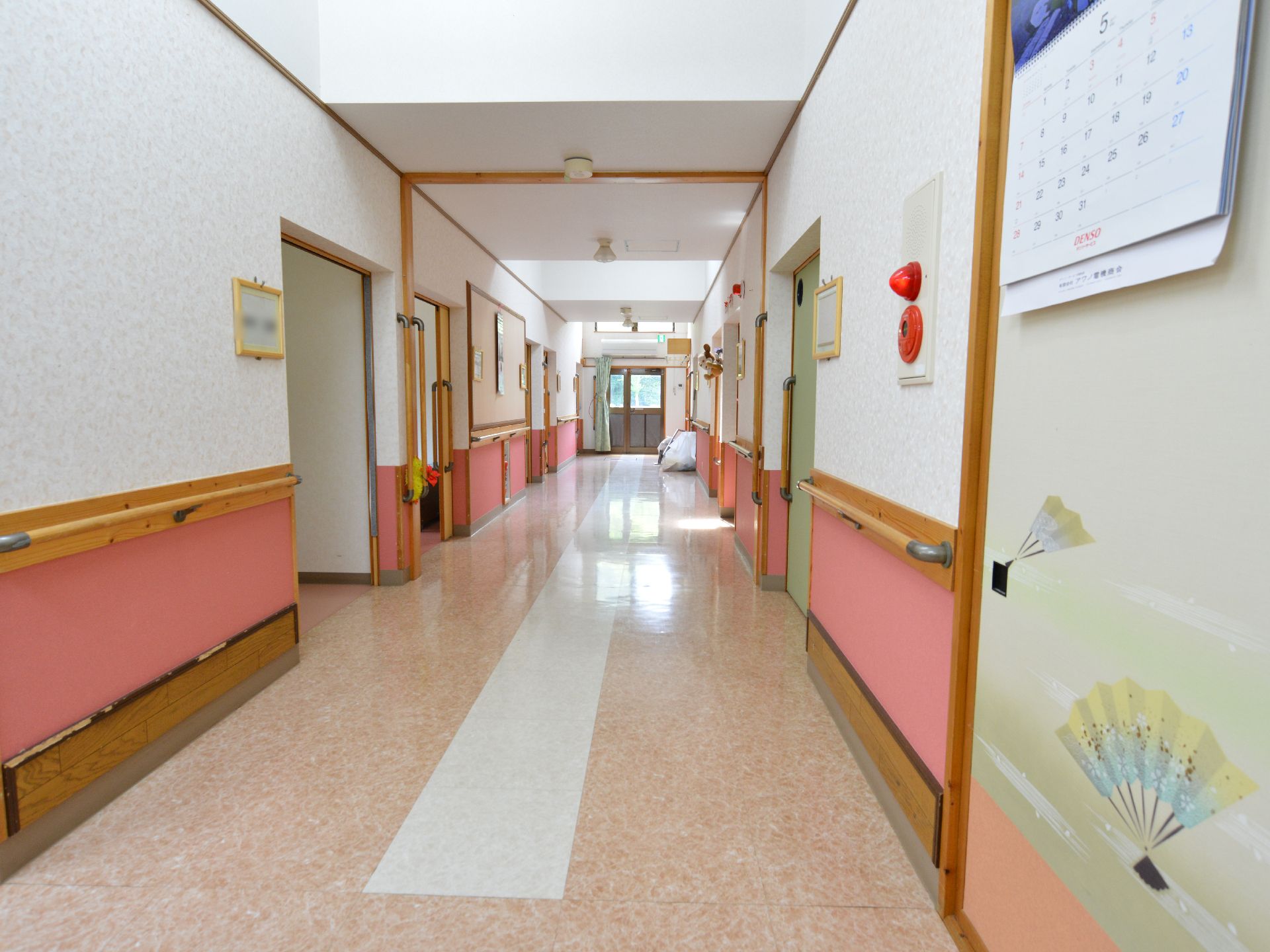 廊下には全ての壁に手すりが設置されて、壁には非常ベルもある。居室の前には名札がかけられていて判りやすくなっている。