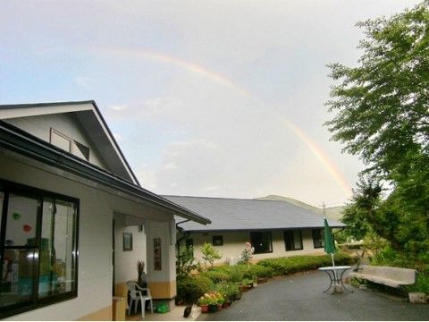 広々した敷地に建つ１階建ての施設である。大きなグレーの屋根が印象的。この日は空に大きな虹がかかっている。