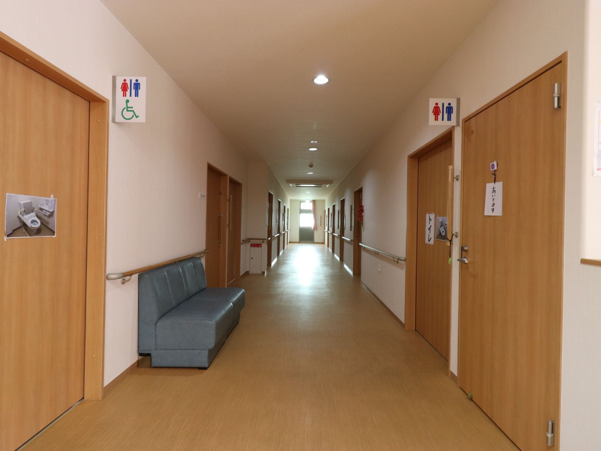リビングの奥は廊下になっていてすぐ横がトイレになっている。廊下の突き当たりは扉になっていて非常口マークが見える。