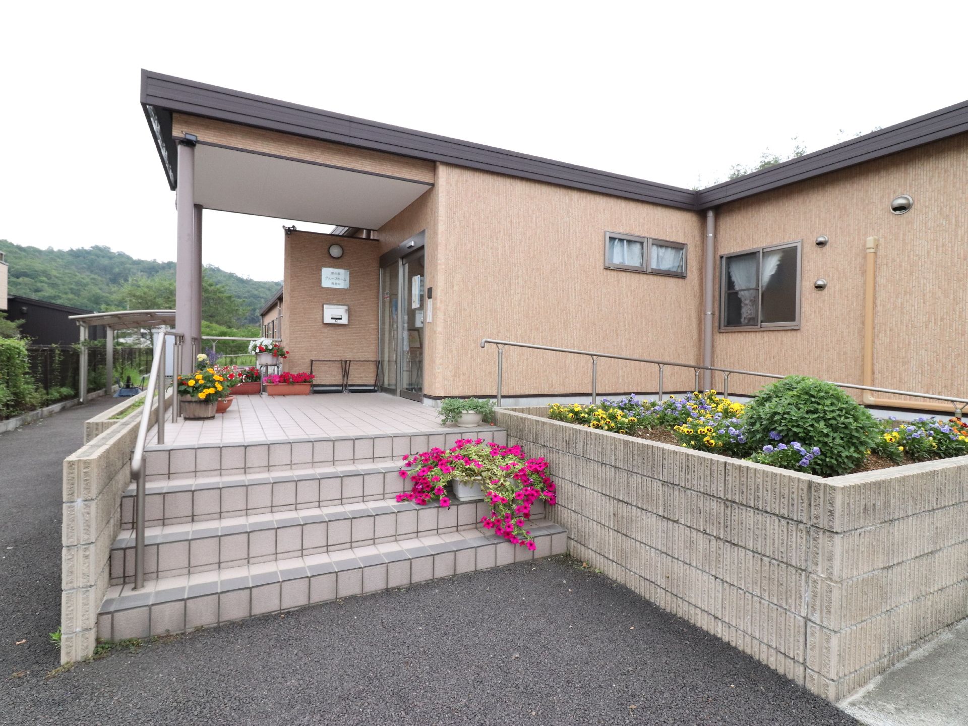 一階建てのすっきりとしたつくりの建物の玄関は階段を4段上がるか、すぐ隣に設置してあるスロープでアクセス可能である。