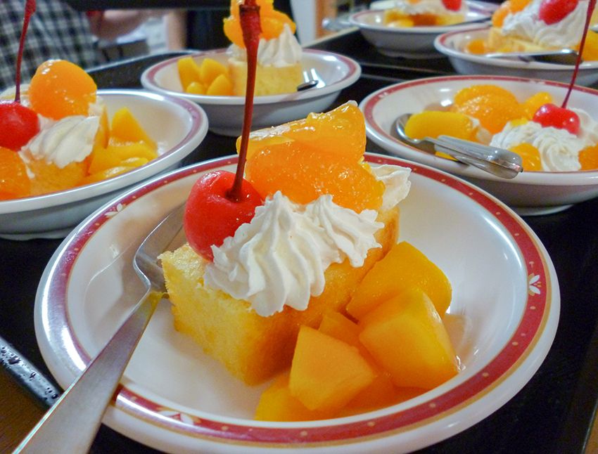 生クリームや、さくらんぼ、みかんなどのフルーツが盛られているスポンジケーキ