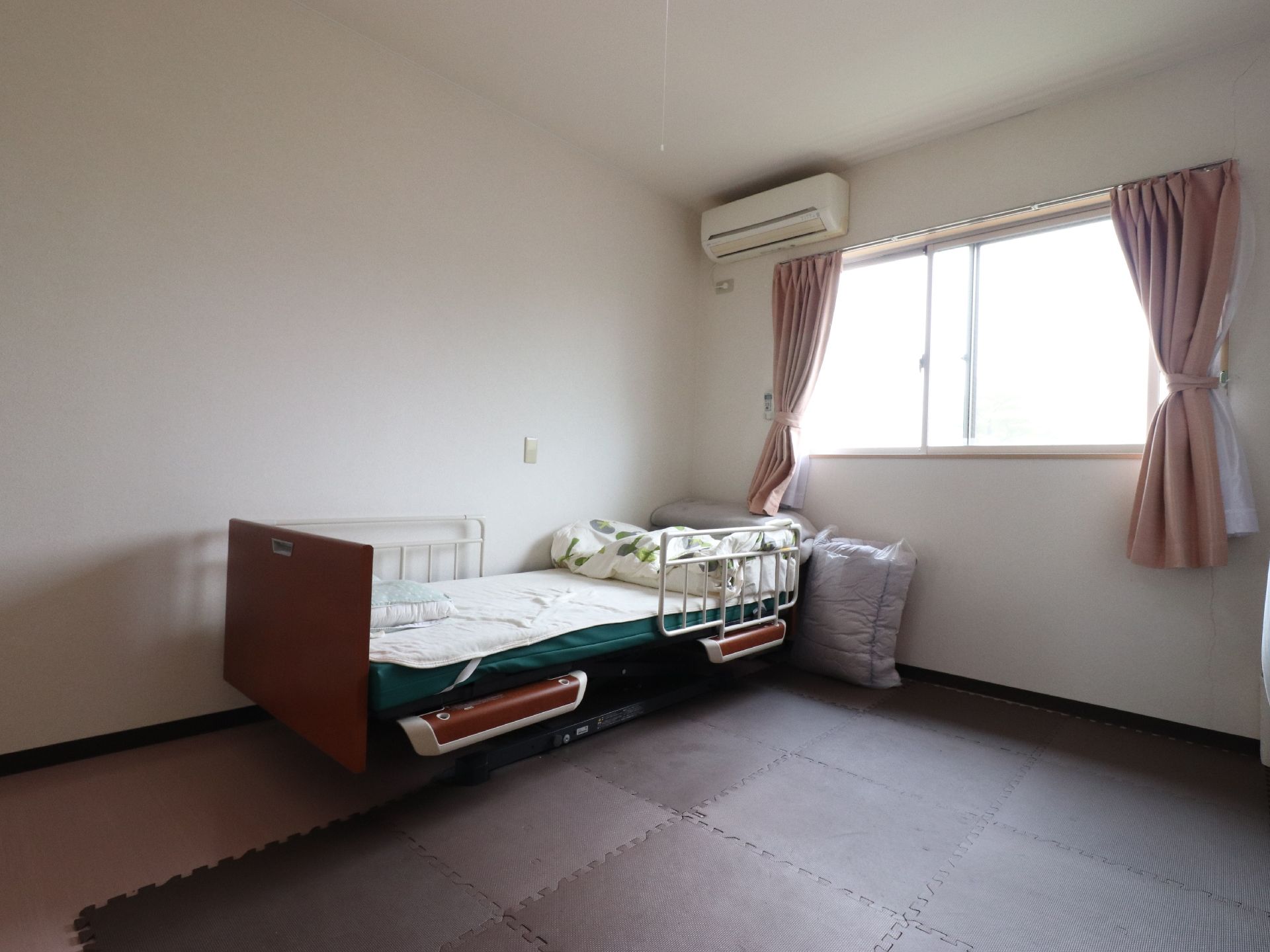 居室は広くてとてもきれい。窓からは明るい日差しと心地いい風が流れてくる。ベッドには手すりもついているので安心できる。