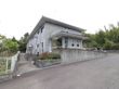 地上から少し坂を上がったところに玄関がある。入口へは階段、またはスロープを使って進む。玄関とスロープの上に屋根がある。