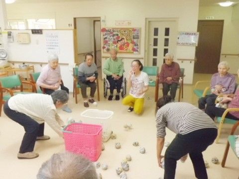 紅白のかごを床に置いて、玉入れを楽しんでいる入居者様