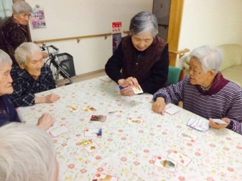大きなテーブルを囲んでカードで遊んでいる女性入居者様