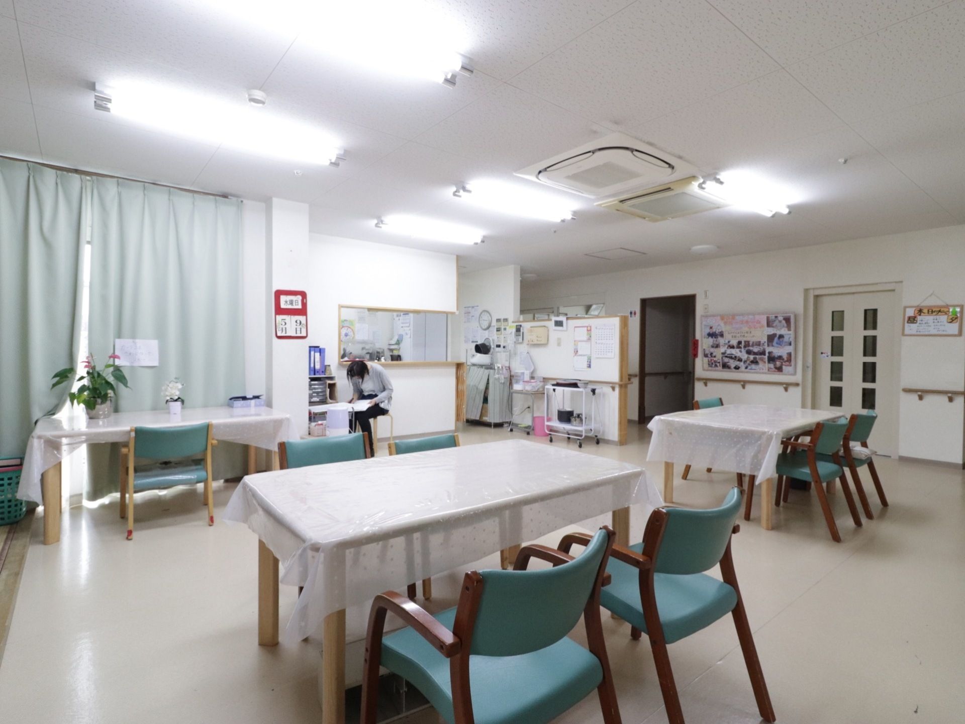 明るいラウンジの壁には手すりが付いているため、入居者様が移動しやすく、壁の掲示板には写真などが飾られている。