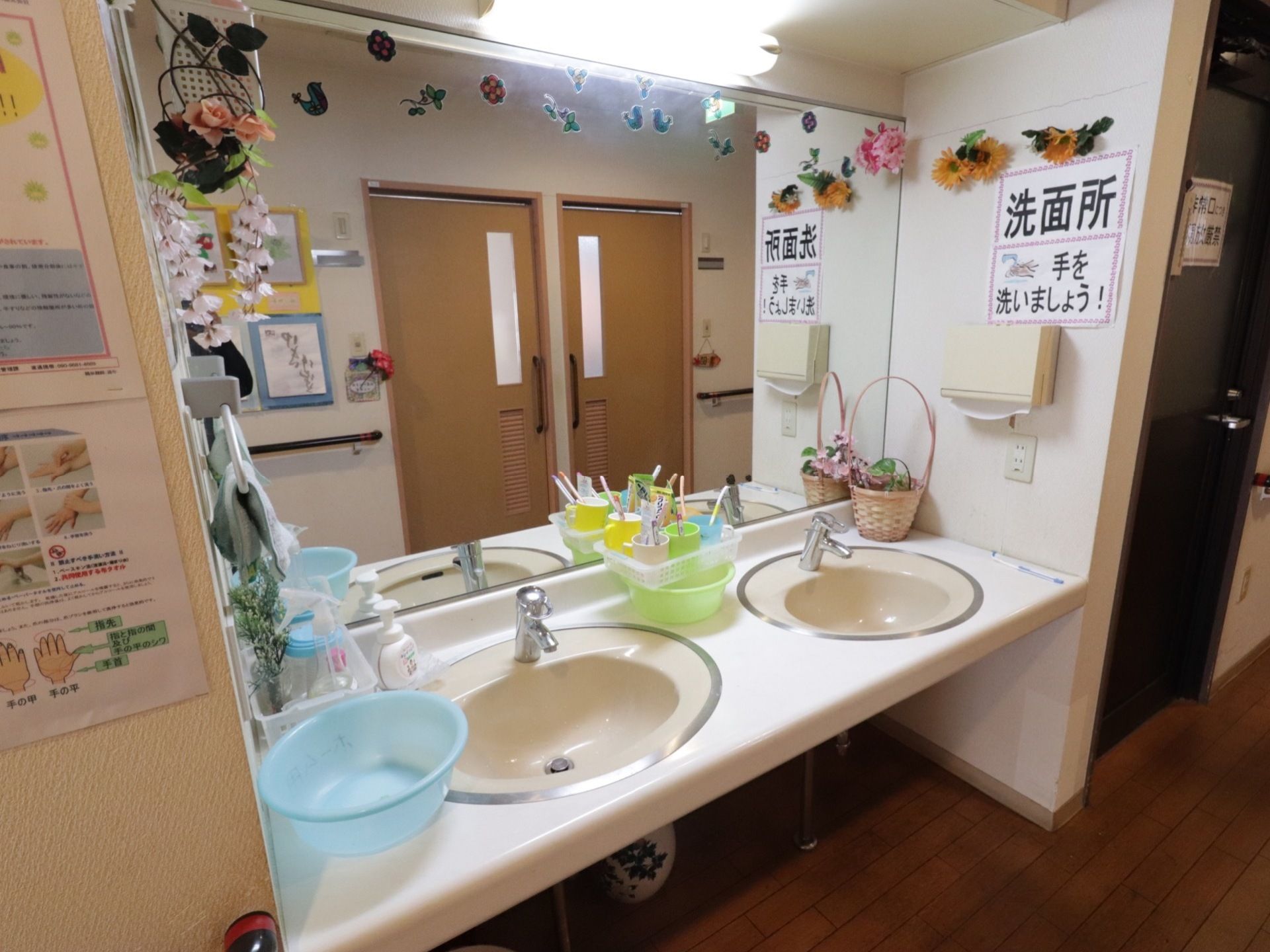 廊下の一角に洗面所が設けられている。壁には、大きな鏡やペーパータオルホルダーが設置されている。ハンドソープが用意されている。