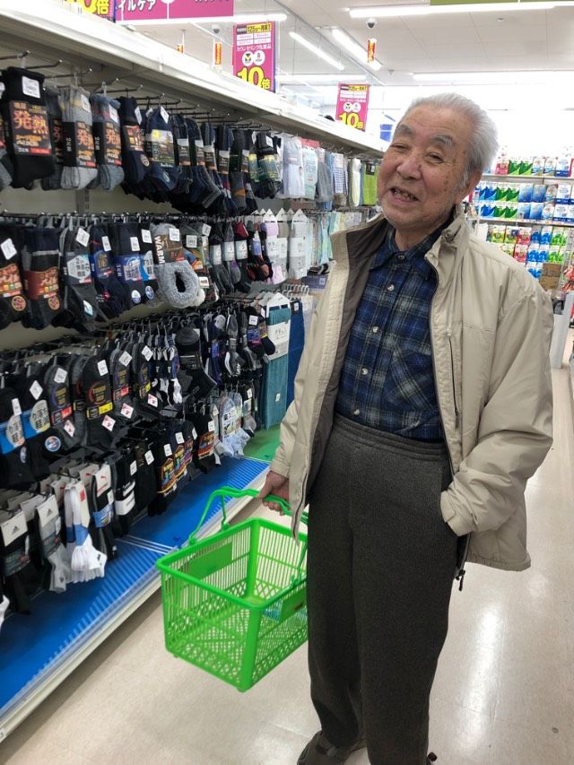 血圧計をつけながら笑っている高齢の男性と、エプロンをつけた女性