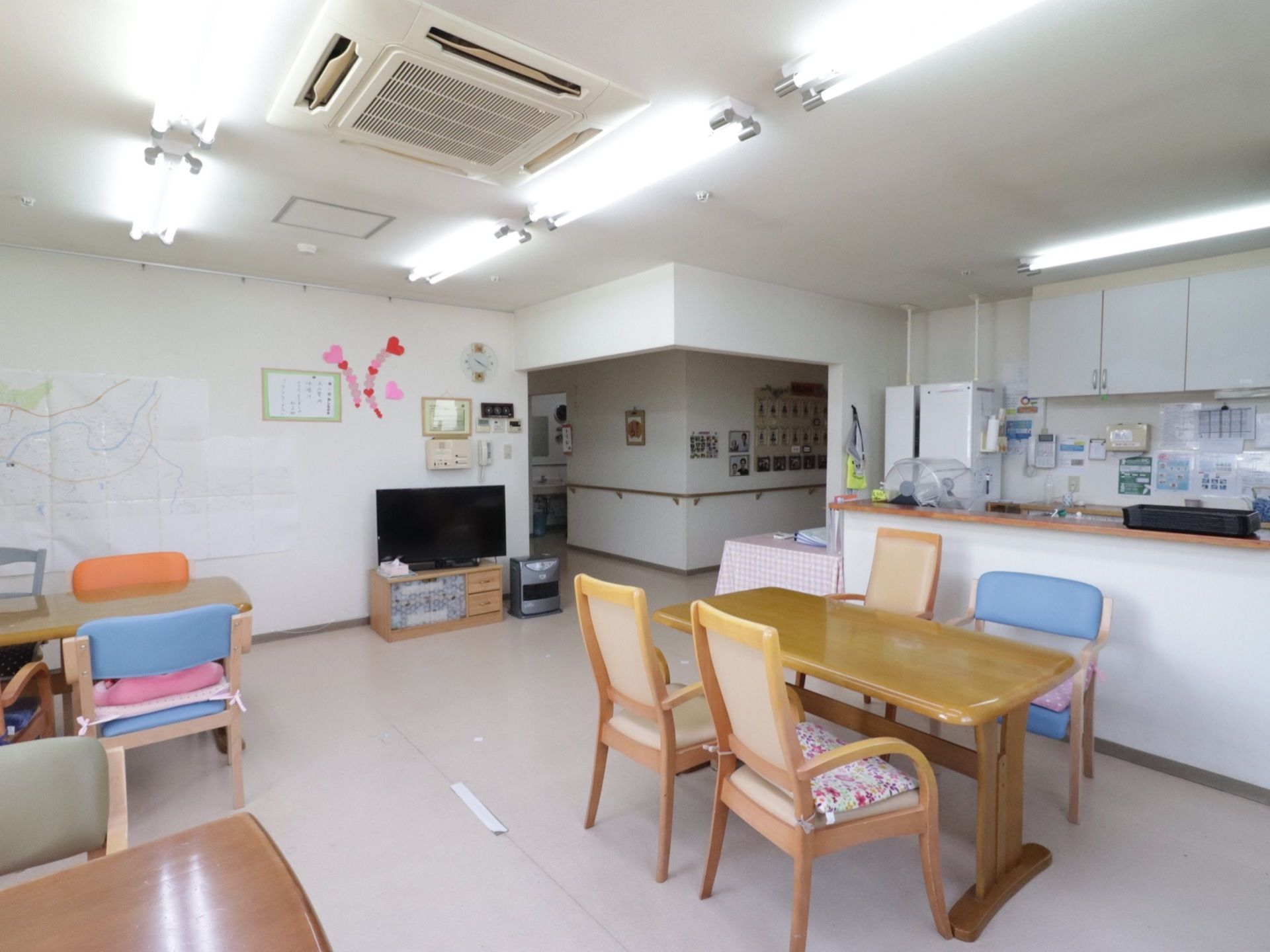 広々とした開放的な食堂である。キッチンが備わっており、４人掛けダイニングテーブルが並べられている。壁際には、大型テレビが設置されている。