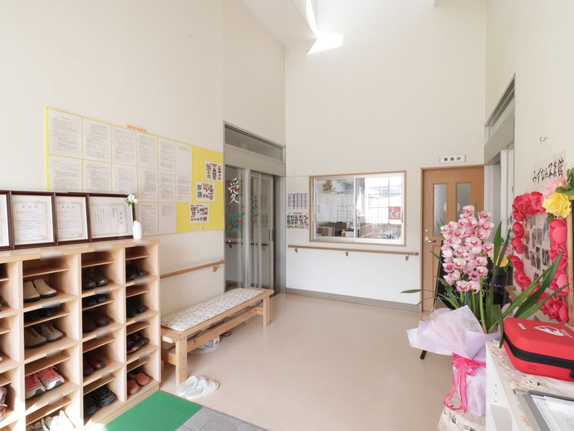 玄関ホールは、天井が高い開放的な空間になっている。左の壁際には、靴箱とベンチが設置されている。右奥には、事務所がある。