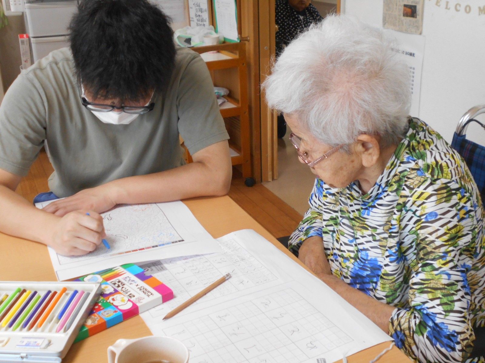 血圧を測定中のスタッフに、笑顔で話しかける入居者様