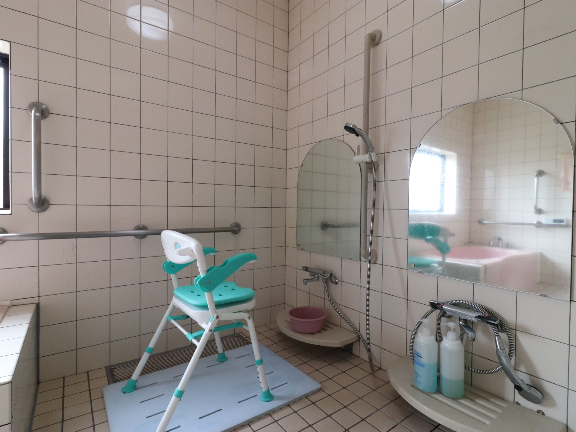 シャワーチェアがあるので、足腰への負担が軽減される。シャワーの前にはアーチ型の鏡が設置されており、シャンプーなどを置く棚も付いている。