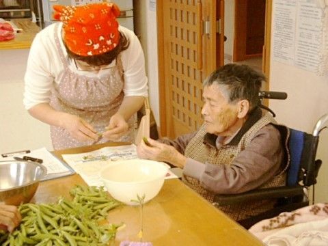 女性スタッフと一緒に野菜の筋取りをしている女性入居者様