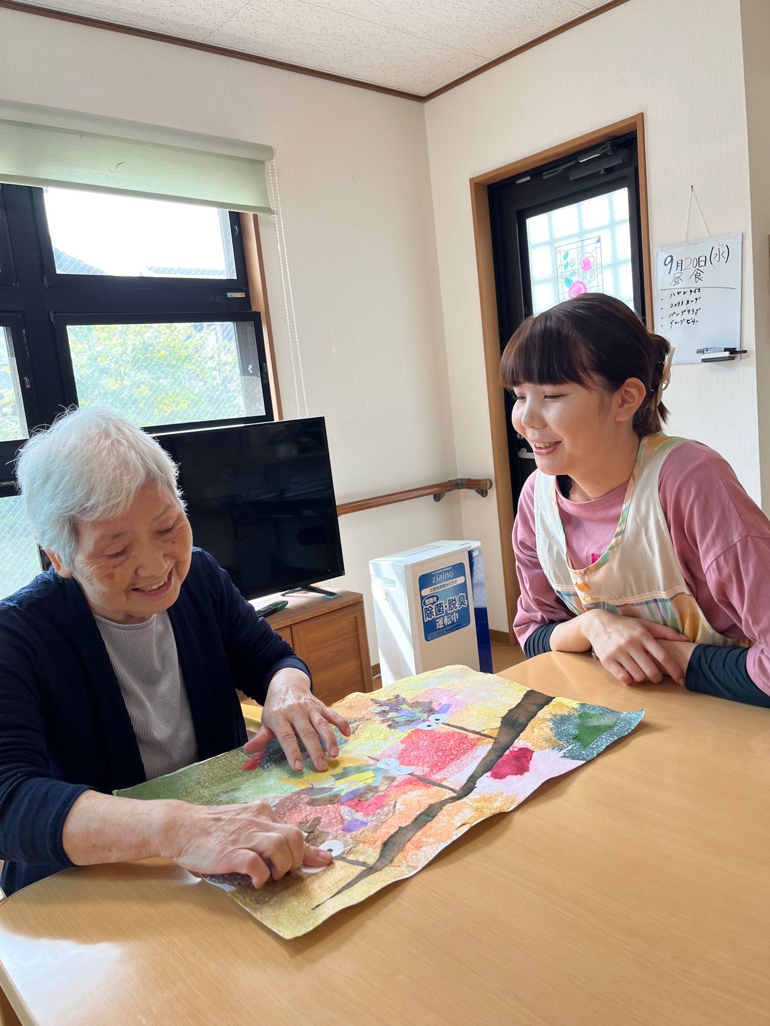 施設内で性別の年齢も違うスタッフが素敵な笑顔で並んで写っている写真。入居者様を沢山の笑顔が迎えてくれる。