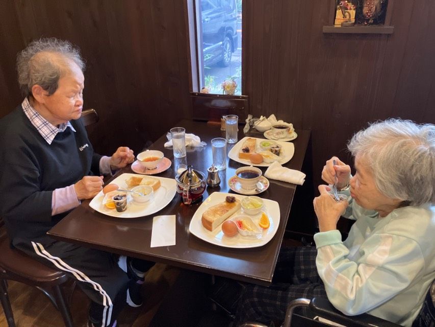 椅子に掛けて血圧測定中の入居者様と笑顔で会話が弾むスタッフ