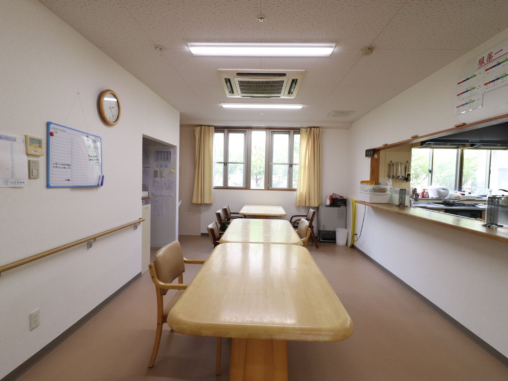 キッチンからカウンターでつながった空間に、椅子とテーブルが置かれている。頭上には照明とエアコンが完備されている。