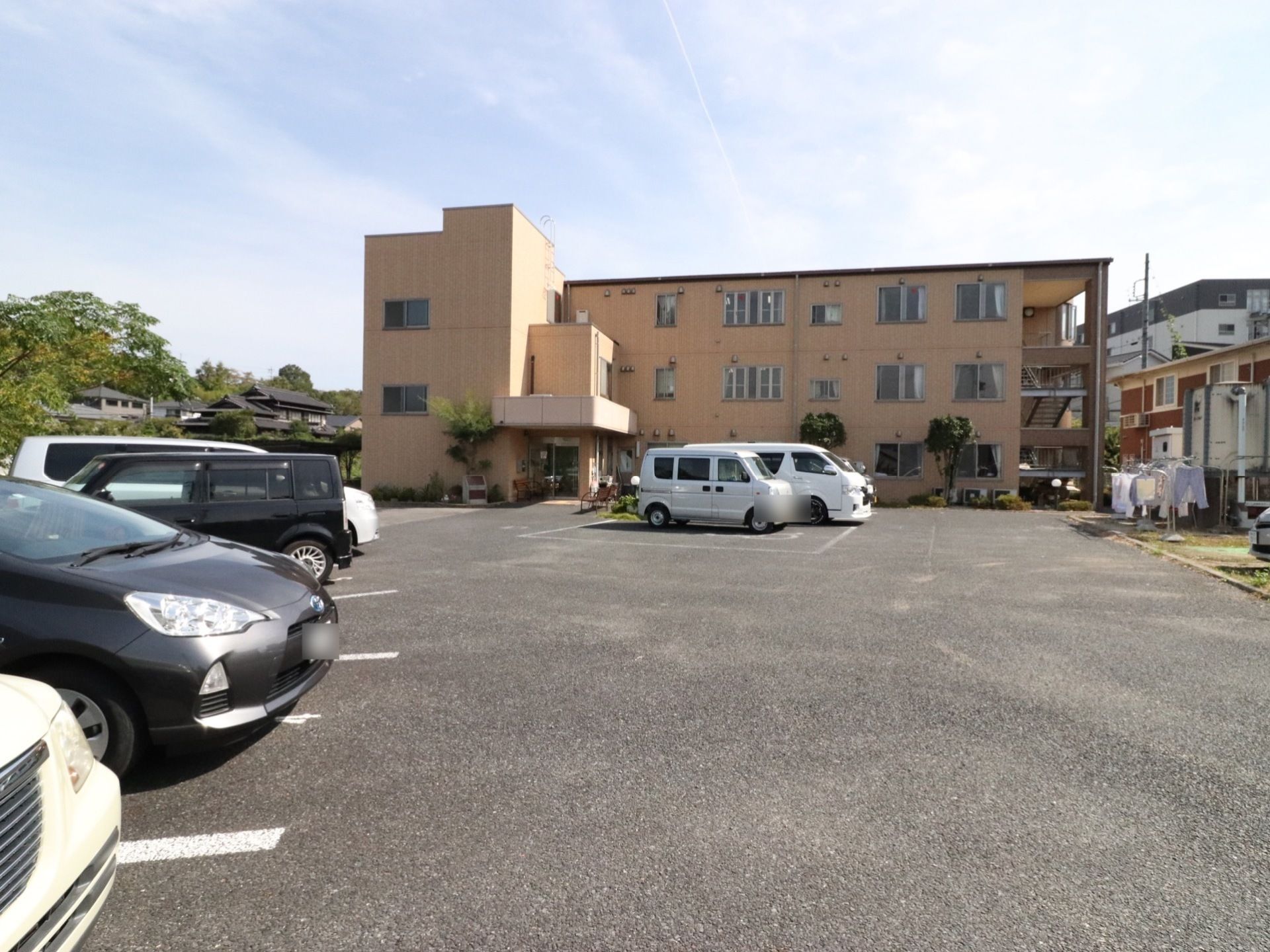 広い駐車場がある。3階建ての大きな建物となっている。落ち着いた雰囲気の外観となっている。洗濯物を干すスペースがある。