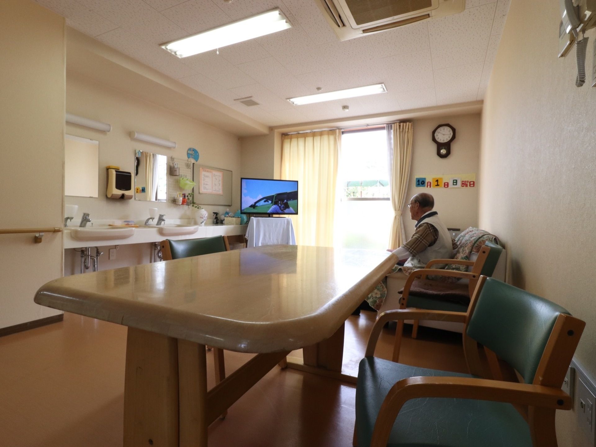 テレビが置かれている。窓があり、たくさんの光が入る。テーブル、椅子、ソファーが置かれている。落ち着いた雰囲気となっている。