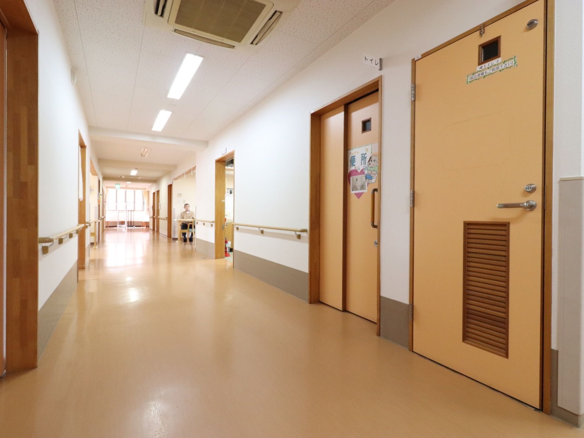 広い開放的な通路である。トイレがある。白い壁なのでとても明るく感じることができる。バリアフリーを考えられた床となっている。