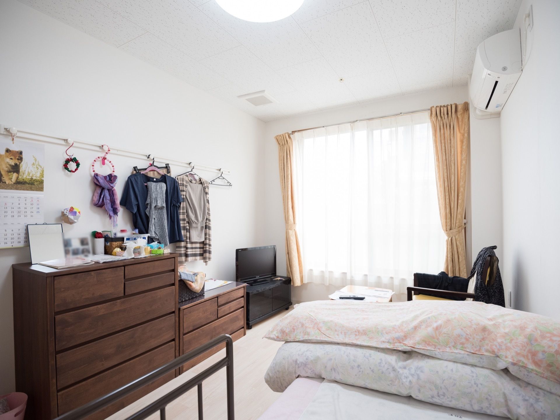 エアコンが完備されている日当たりの良いワンルームの居室。壁にはハンガーが掛けられるようになっている。
