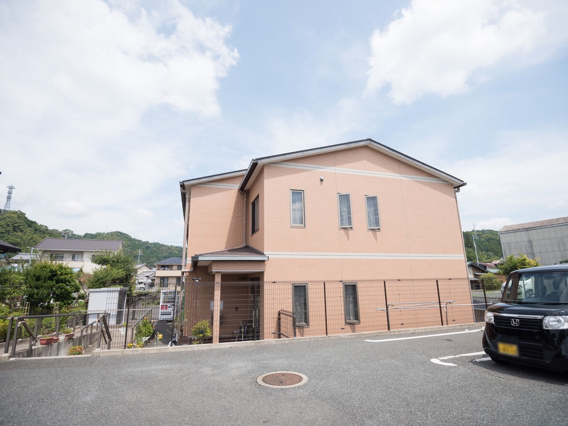 住宅街の中にある、暖色系を基調とした２階建ての建物である。縦長のすべり出し窓が並び、いくつかは窓が開いている。