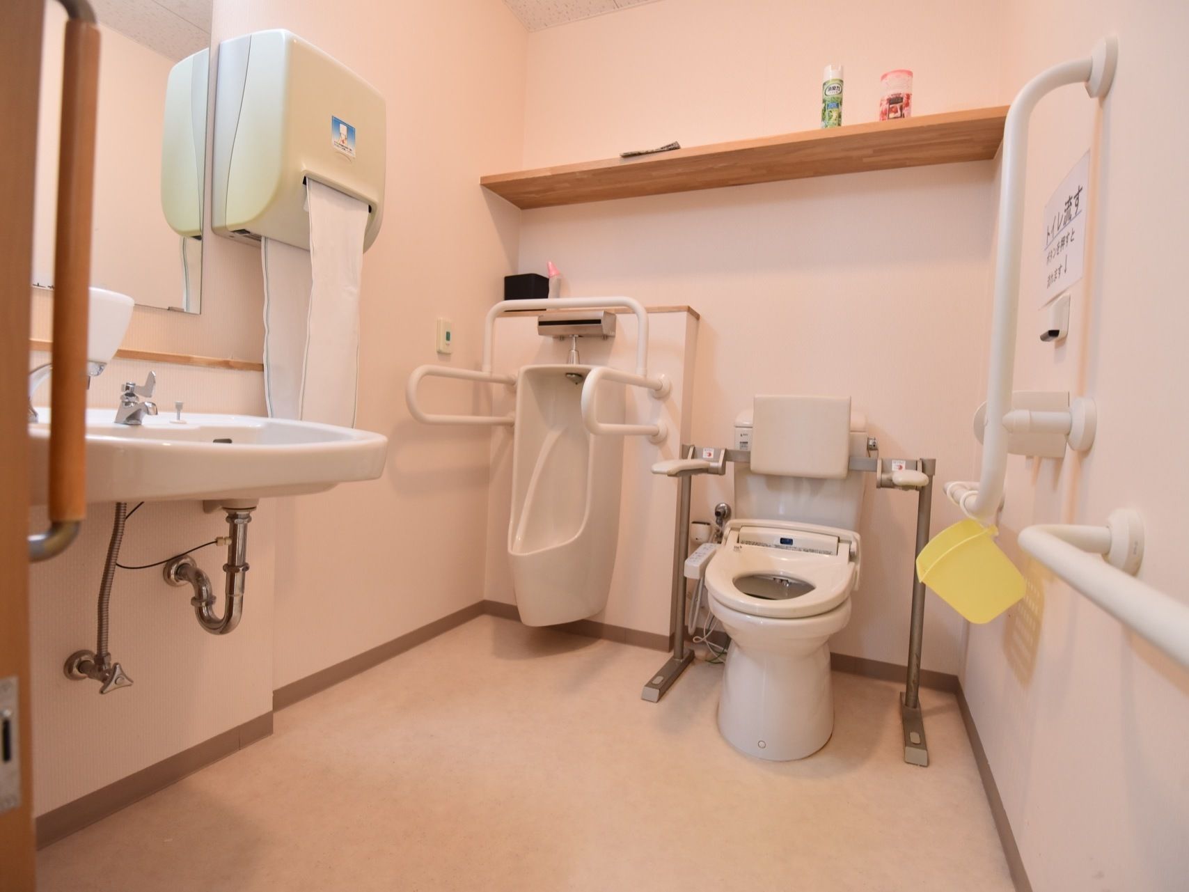 フットレスタイプの洗面台が備えつけられているトイレで、横の壁には手拭き用のタオルが用意されている。扉はスライド式となっている。