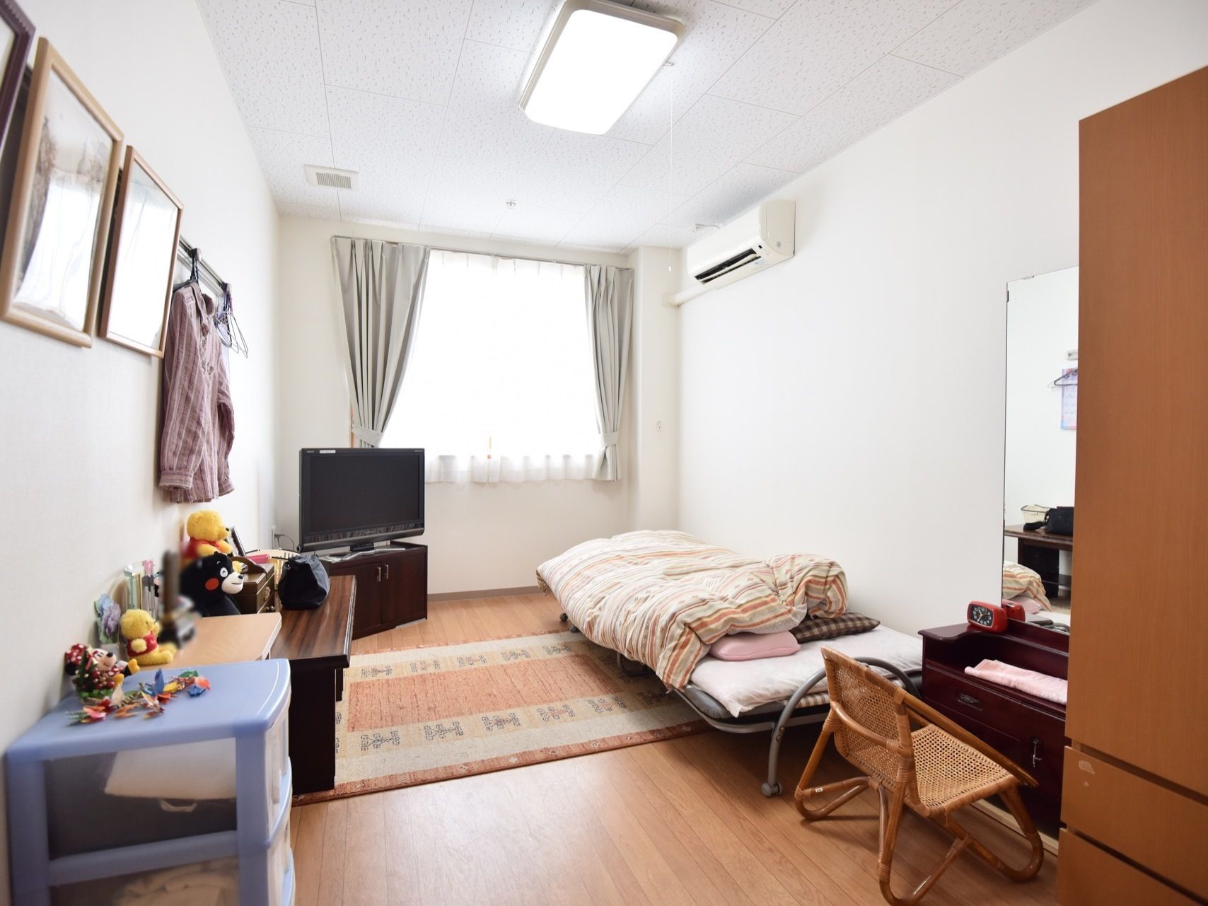 木製の洋服ダンスの横に、大きな鏡のついた化粧台が置かれている。フロアの隅にはテレビが設置されている。
