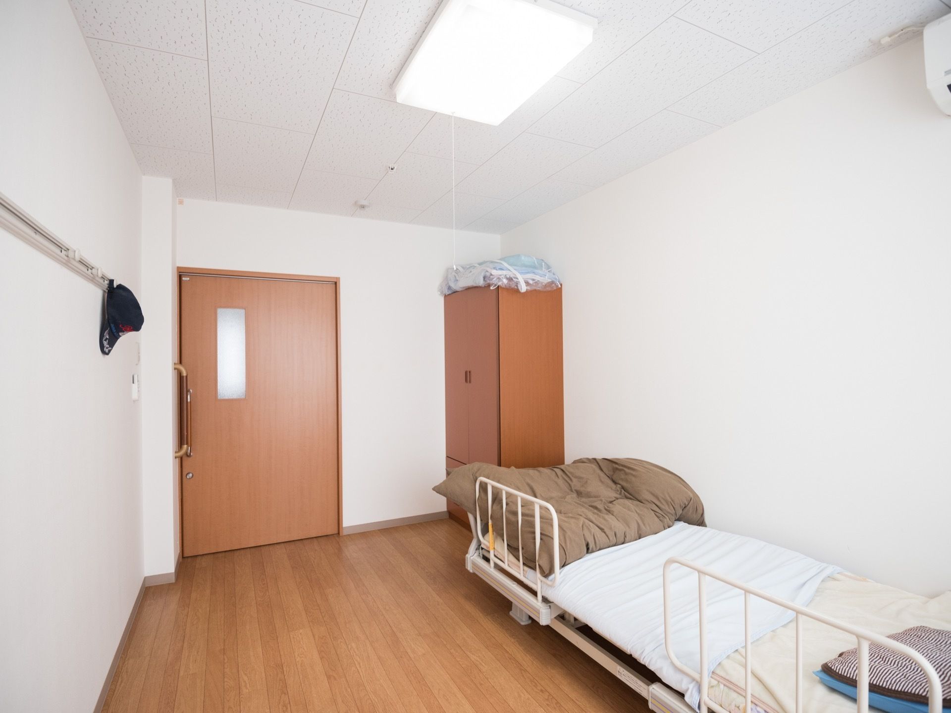 木目調の洋部屋である。扉に明かり窓が設置されている。そばには、両開きの木製クローゼットが置かれている。