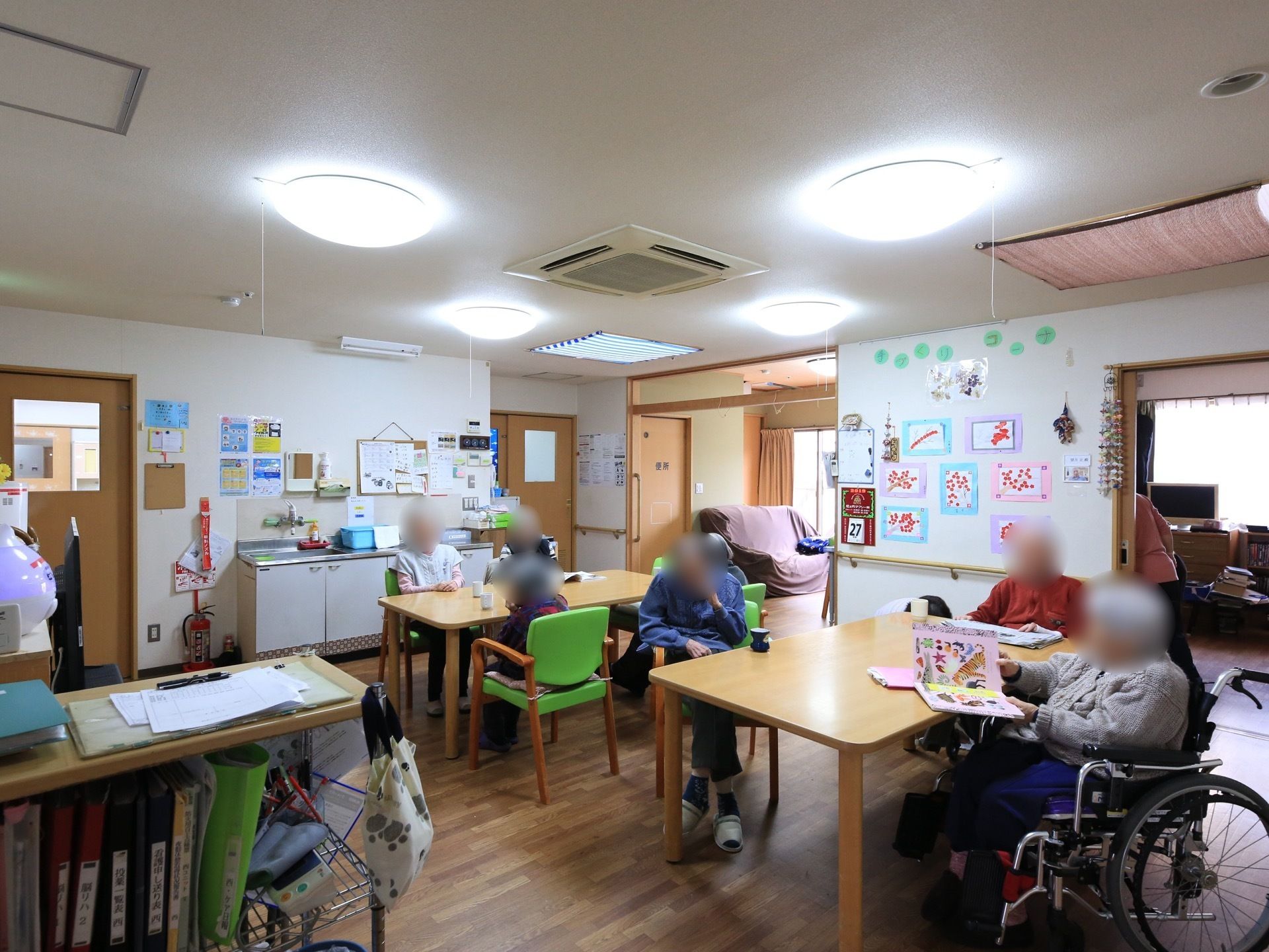 食堂の壁にはカラフルな台紙に貼られた入居者様の作品などが飾られていて賑やかな雰囲気である。壁際には流しが設置されている。