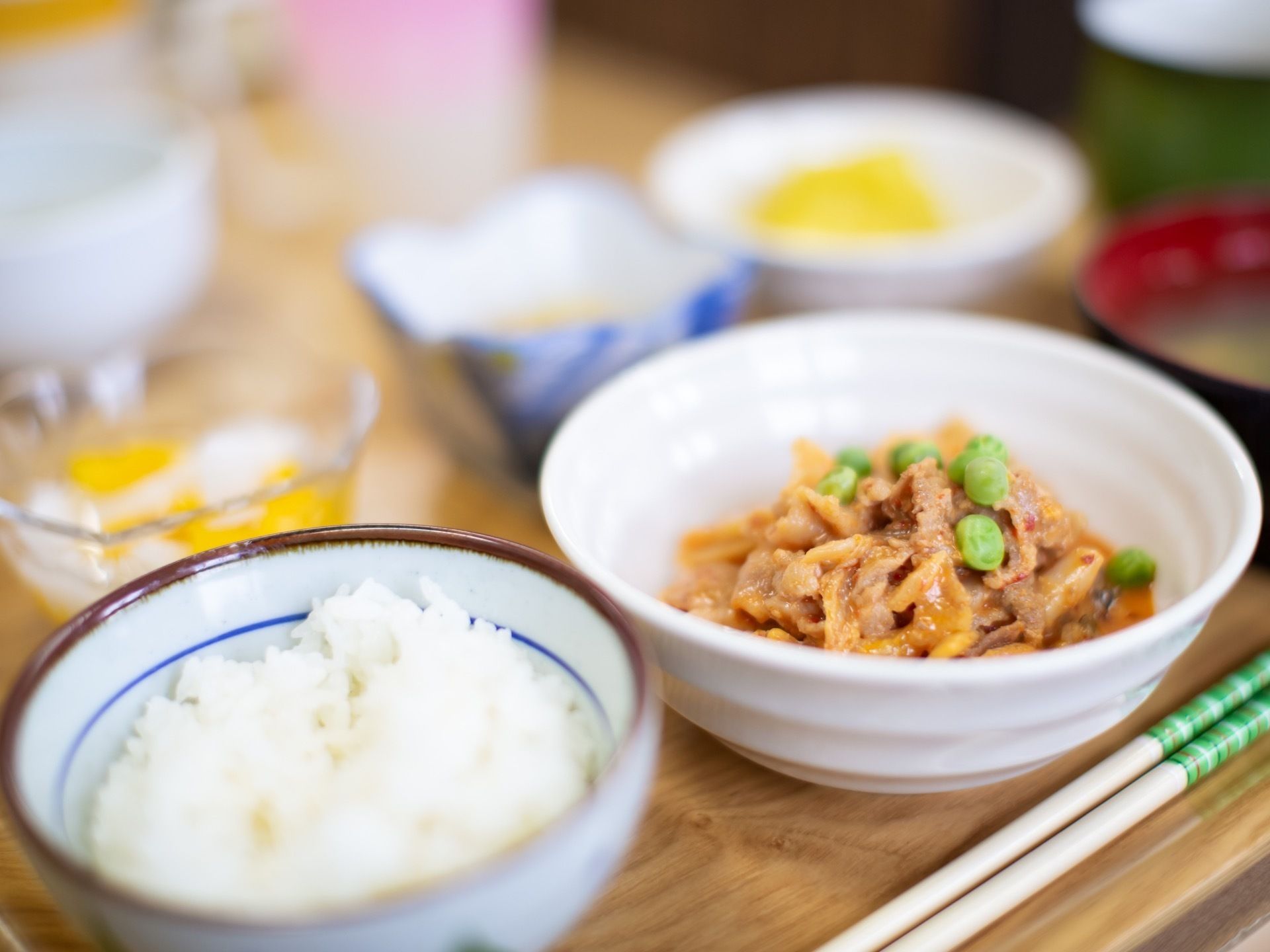 木のお盆の上に、ご飯と味噌汁、肉料理のお皿、副菜の小鉢などが、綺麗に並べられている。デザートもついている。