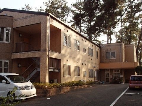 「愛の家グループホーム 三保松原」の外観。駐車スペースのある、鉄筋コンクリート造2階建てのグループホーム。