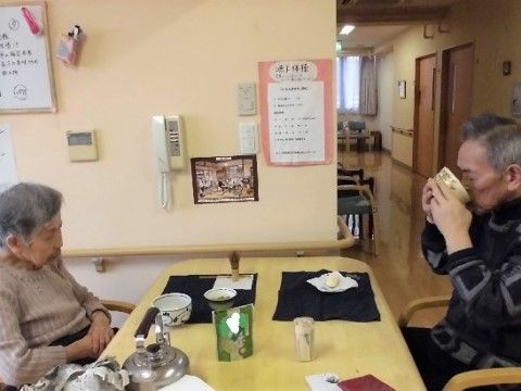 向かい合って座って和菓子とお茶をたのしんでいる入居者様達