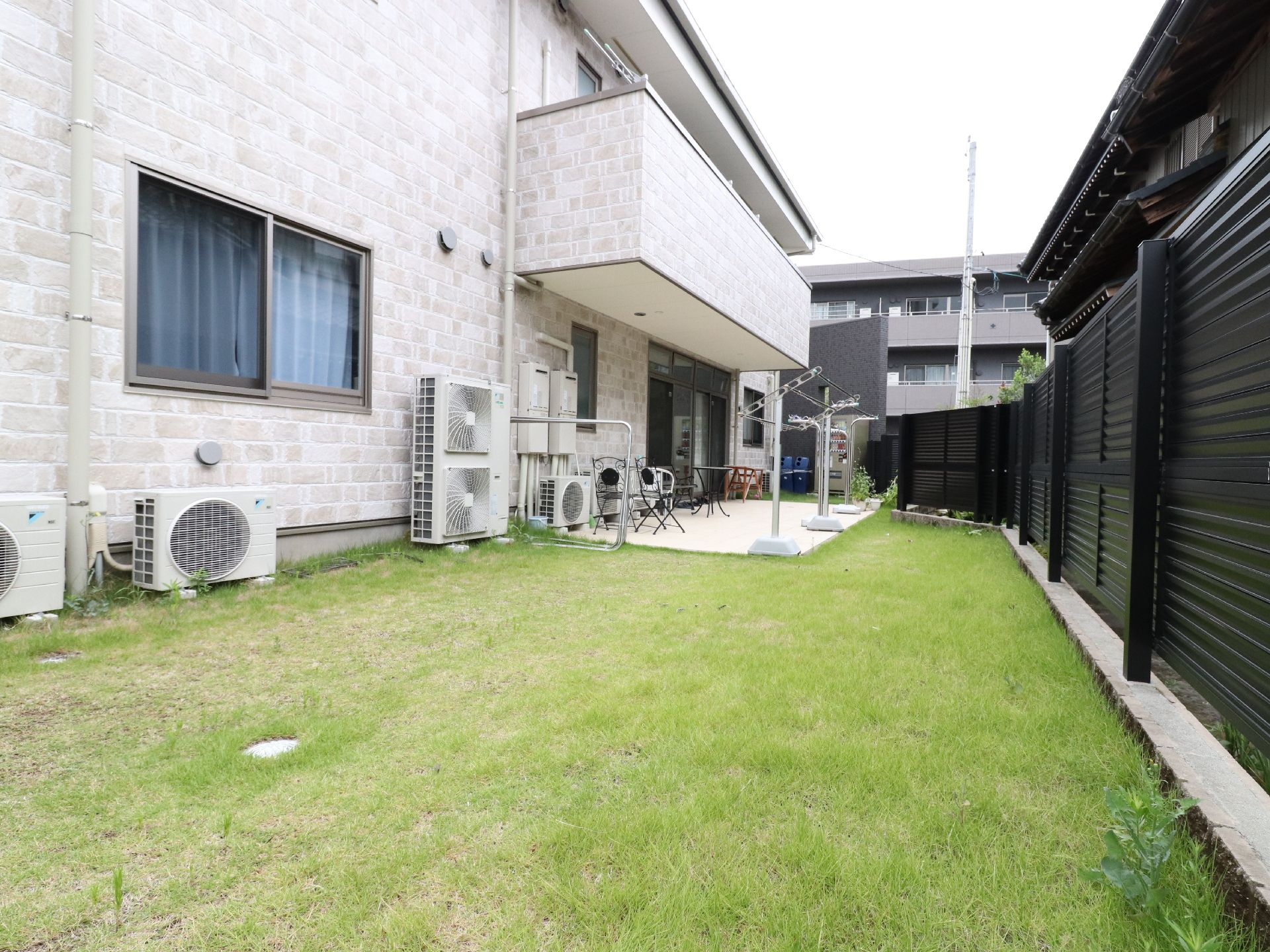 庭の側からベランダを眺めたアングル。頭上の2階にも洗濯物干し場があるのが見える。近辺にそれほど高い建物はない様子。
