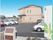ベージュ色の一般住宅のような２階建ての建物が建っている。アスファルトで整備された駐車場にたくさんの車が停められている。