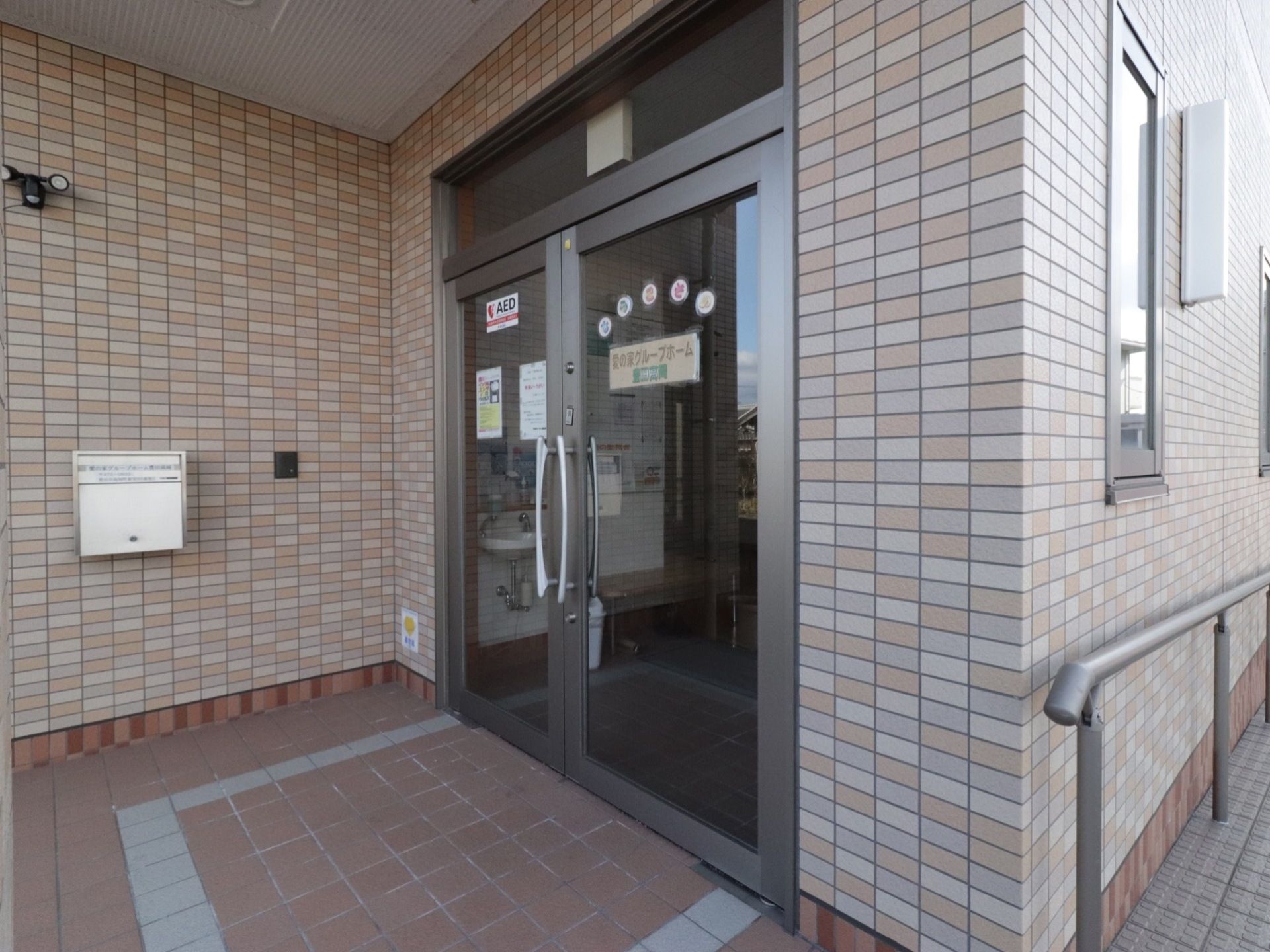 玄関の周りはレンガ調の壁になっている。入り口はガラスがはめ込まれている。また、両方の扉が開く式になっている。