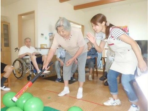 女性スタッフの声かけを受けながら遊んでいる女性入居者様
