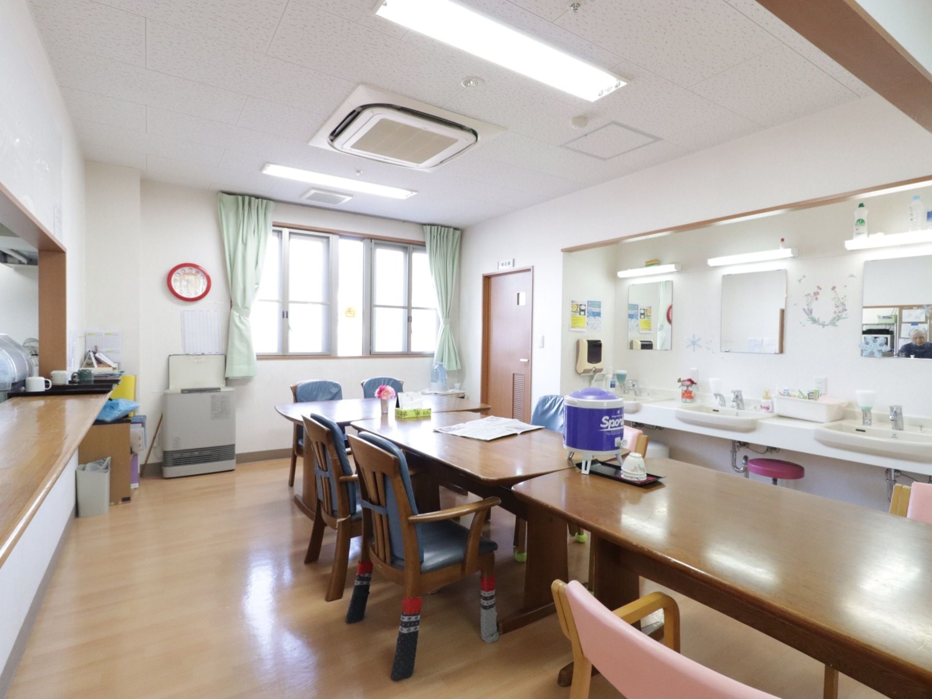 日当たりのよい明るい食堂である。ダイニングテーブルが横並びになっている。椅子はひじ掛け付きでゆったり座れる。洗面スペースが3ヶ所ある。