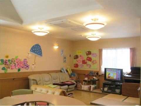 広々としたリビングには、ソファやテレビが設置されており、畳でくつろぐこともできる。壁際にはピアノやレクリエーションの道具が収納されている。