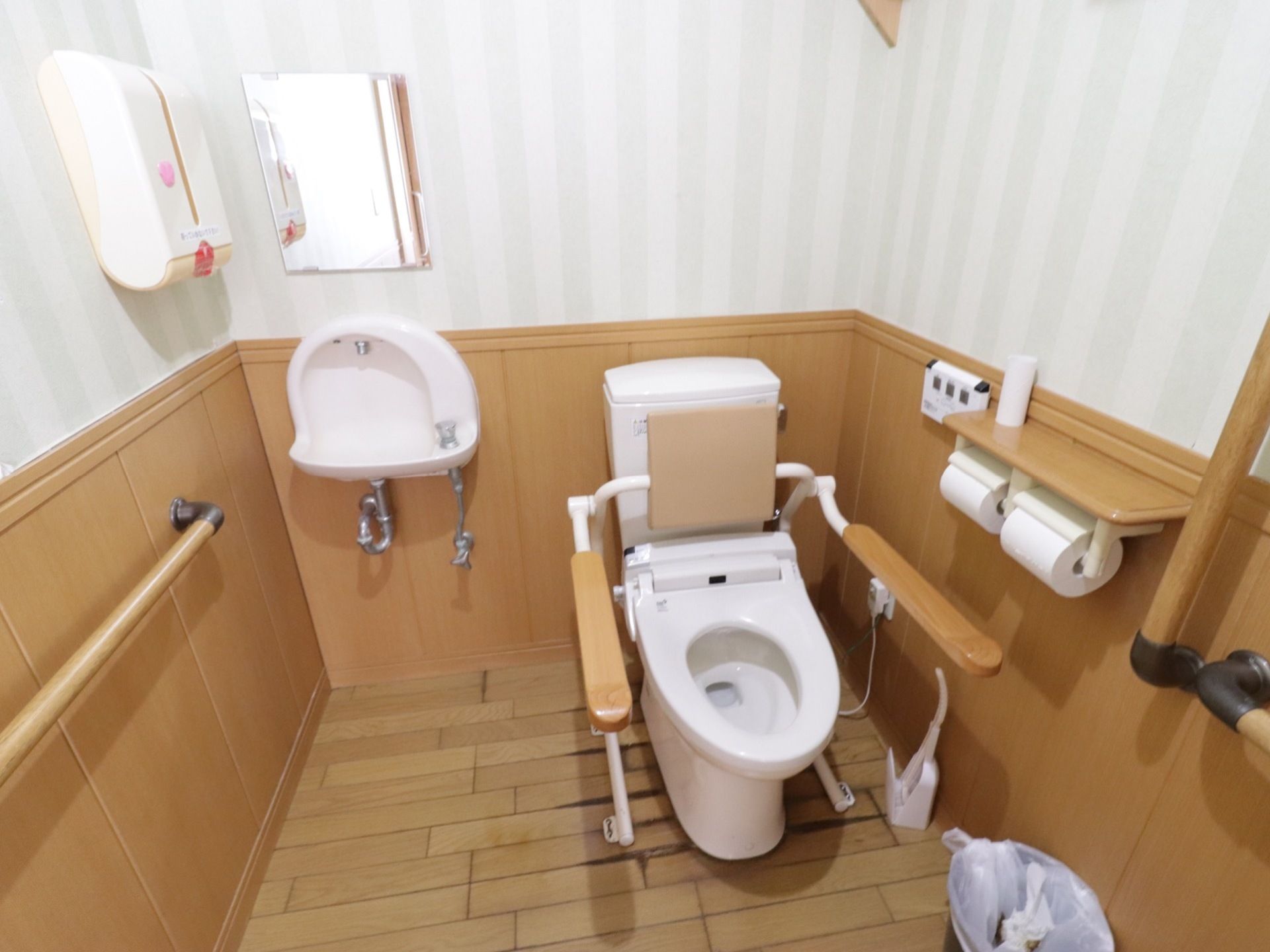 トイレは床や腰壁、手すりなどがウッド調でまとめられている。淡いグリーンのストライプの壁紙との組み合わせが、洒落た雰囲気を演出している。