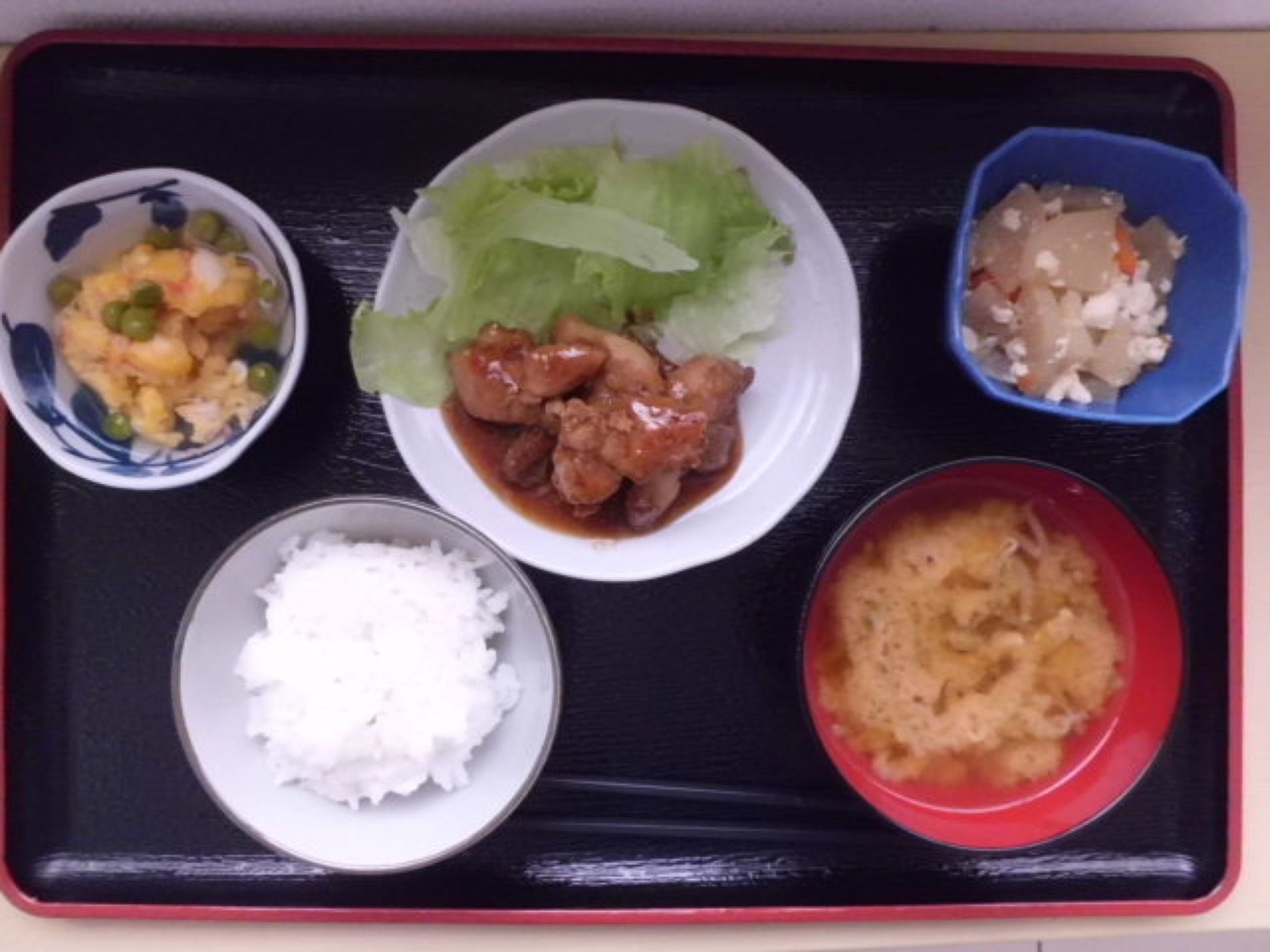 メインの料理と小鉢が２点、ご飯、味噌汁が盛り付けられ、トレーにのっている。盛り付けや器にも配慮している。