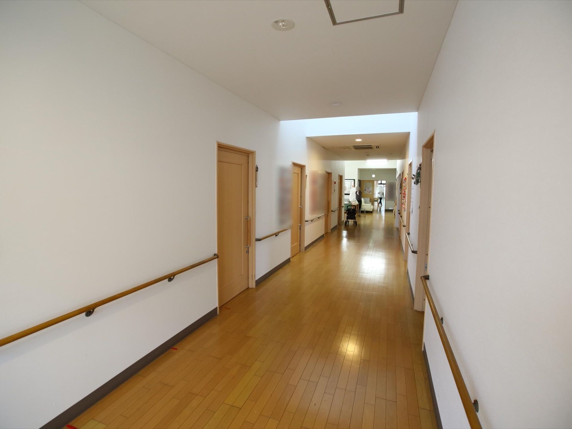 とても幅の広い通路。通路に沿って手すりも壁に備えられている。通路の先にはソファなどが置かれたスペースがある。