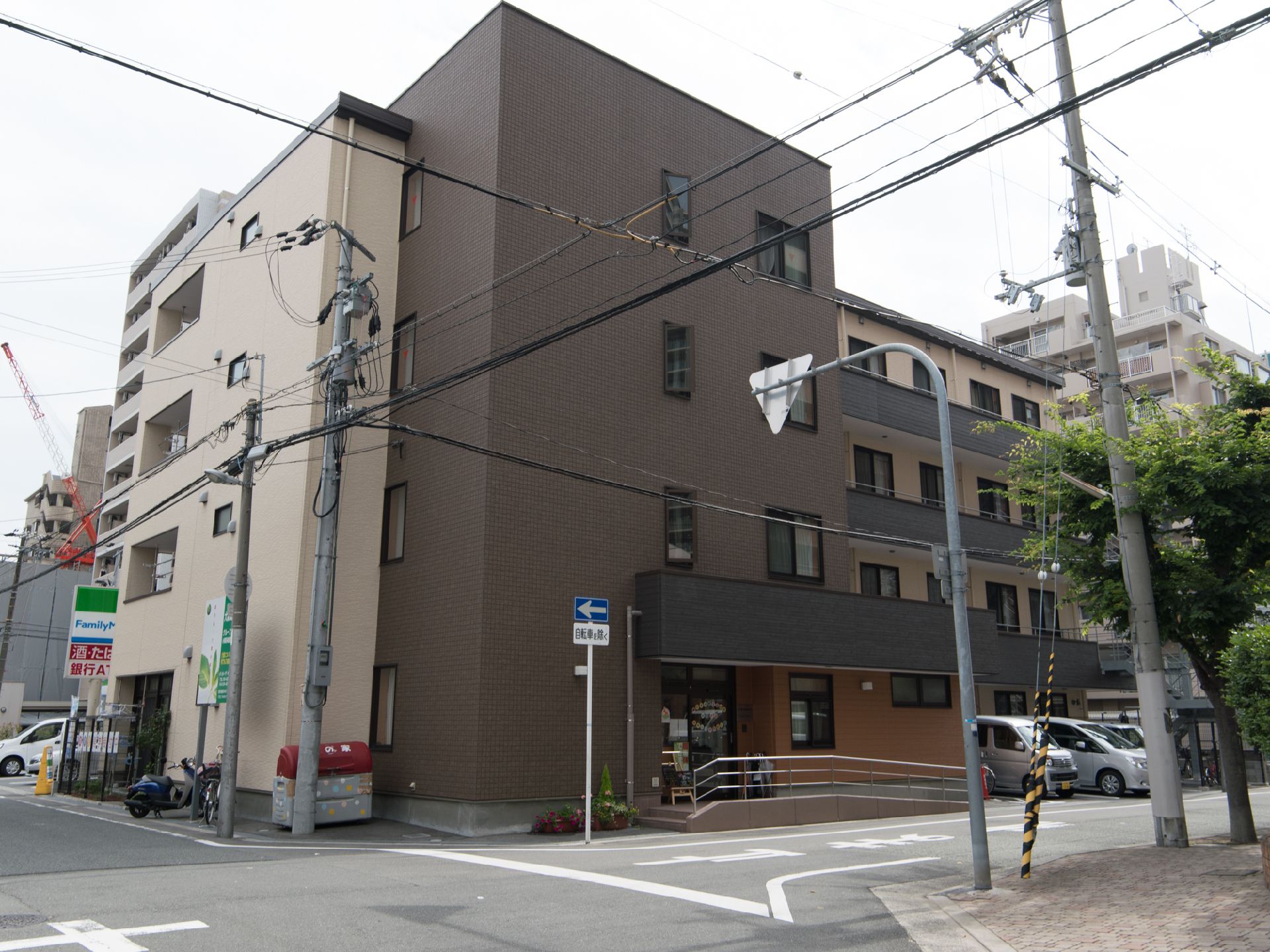 住宅街の一角にある施設で、スロープが玄関に取り付けてある。玄関わきに駐車場が設けてある。傘立てがある。