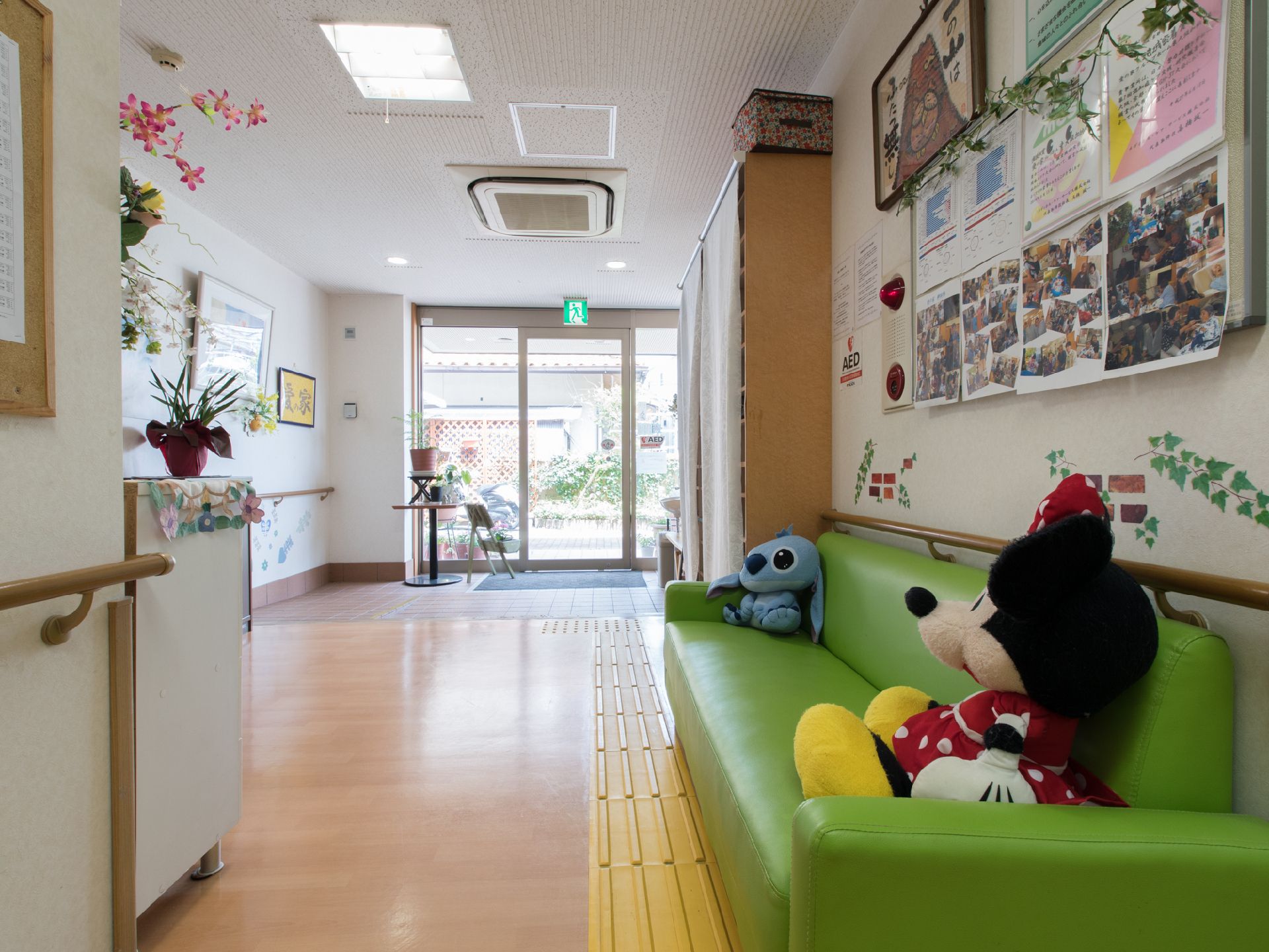 スタッフルーム側から見た玄関で、ガラスドアのため、外がよく見える。観葉植物が丸いテーブルの上に置いてある。