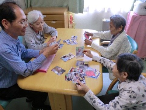 テーブルに集まって写真を見ながら話をしている入居者様たち