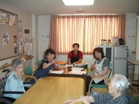 テーブルを囲んで座っている２名の女性入居者様とスタッフたち