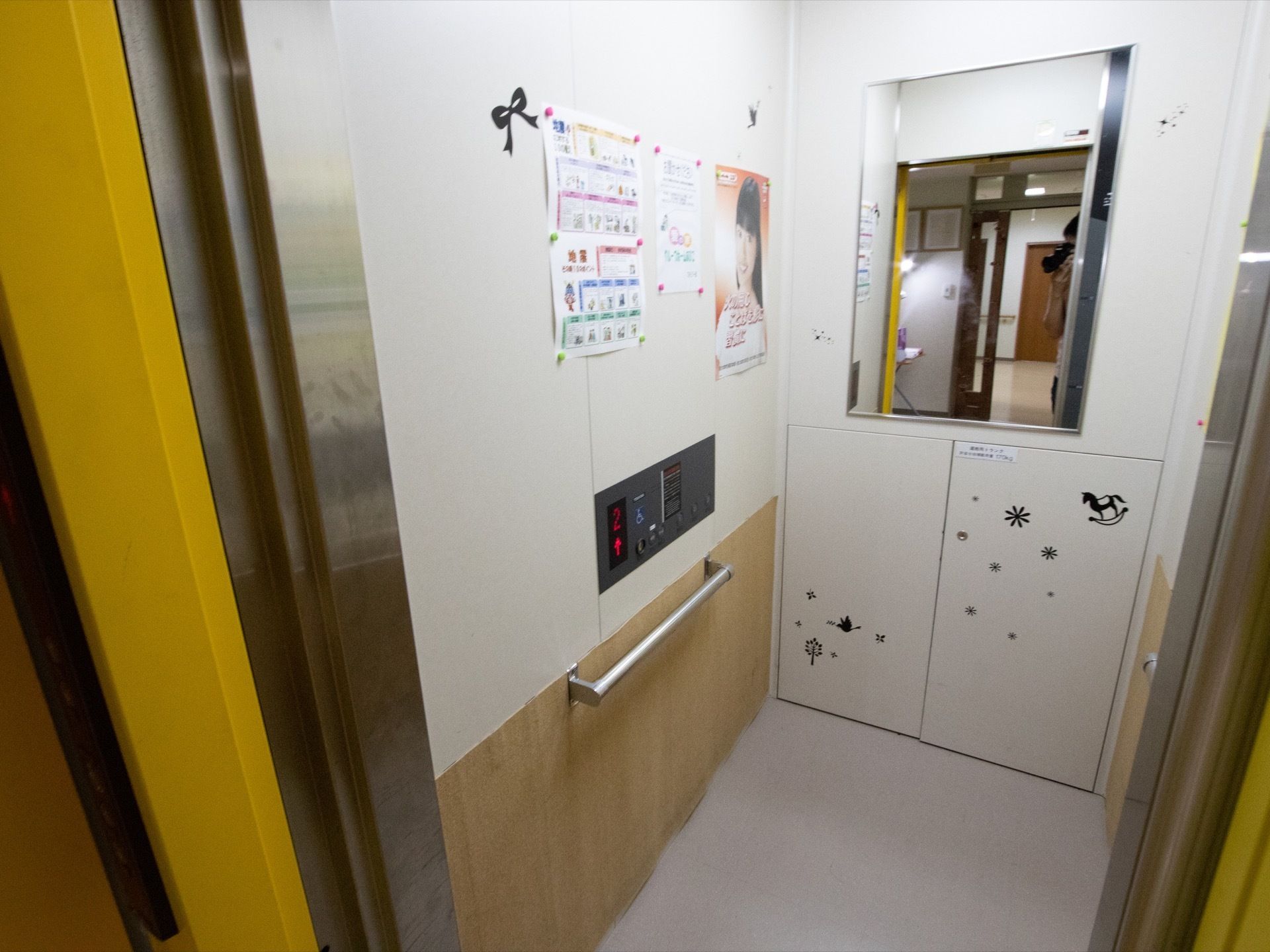 開口部が黄色で施された、おしゃれなエレベーターである。エレベーター内に手すりが完備され、安心して乗り降りできる。